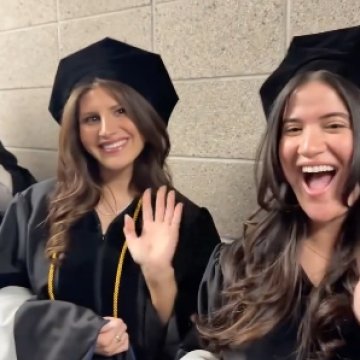 Graduates waving to the camera right before commencement begins