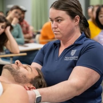 a massage therapy student practicing massage techniques on a mock patient in a classroom.