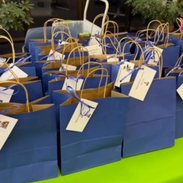 A table of blue gift bags with tags, arranged for a campus event.