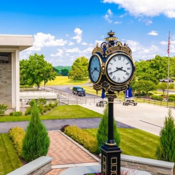 The ornate Northeast College of Health Sciences clock tower surrounded by lush green campus grounds on a sunny day.